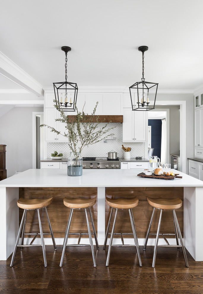 Large beach style eat-in kitchen in Chicago with an undermount sink, beaded inset cabinets, white cabinets, quartz benchtops, white splashback, ceramic splashback, stainless steel appliances, medium hardwood floors, with island, brown floor and white benchtop.