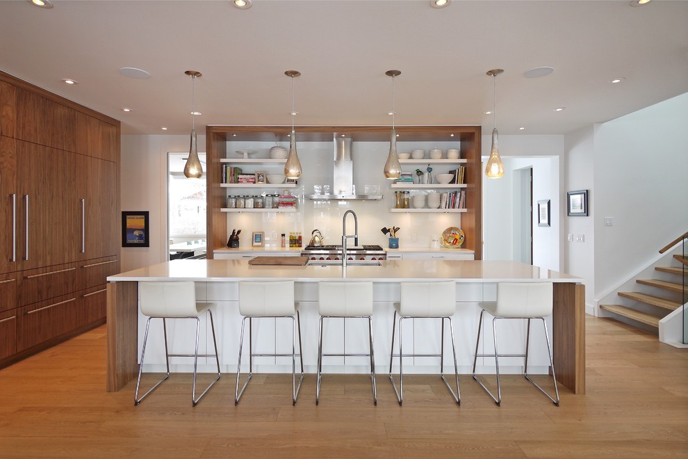 Large contemporary kitchen in Calgary with an undermount sink, quartz benchtops, white splashback, glass sheet splashback, stainless steel appliances, medium hardwood floors, with island, open cabinets and white cabinets.