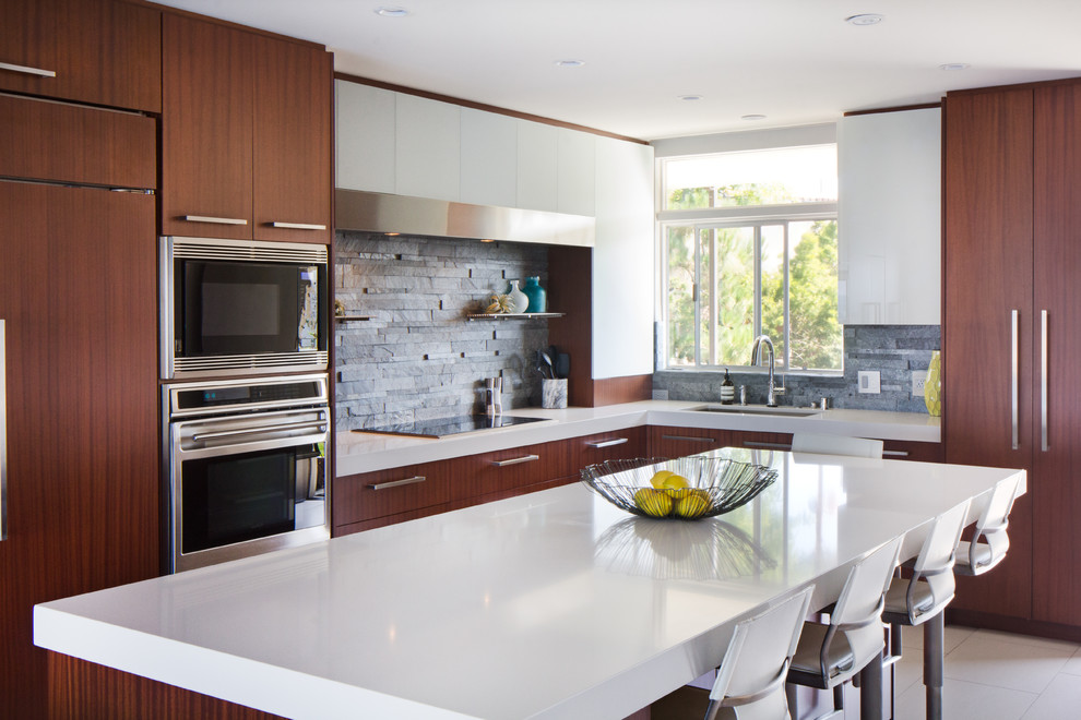 This is an example of a small modern l-shaped open plan kitchen in Los Angeles with an undermount sink, flat-panel cabinets, medium wood cabinets, quartz benchtops, grey splashback, stone tile splashback, stainless steel appliances, limestone floors, with island and white floor.