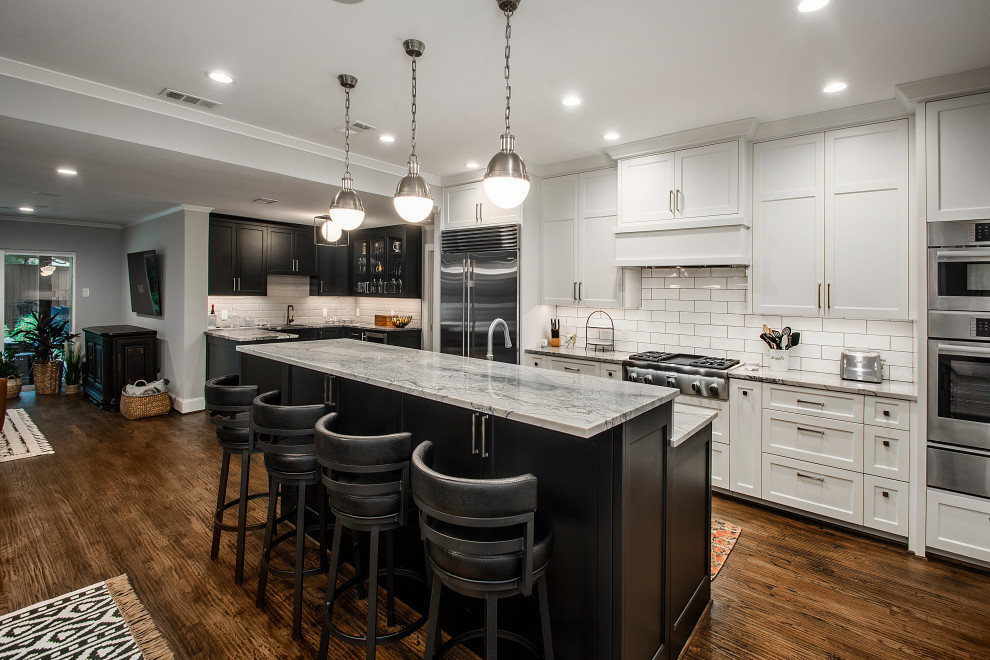 Inspiration for a mid-sized transitional single-wall open plan kitchen in Dallas with dark hardwood floors, brown floor, a double-bowl sink, recessed-panel cabinets, white cabinets, quartz benchtops, white splashback, ceramic splashback, stainless steel appliances, with island and grey benchtop.