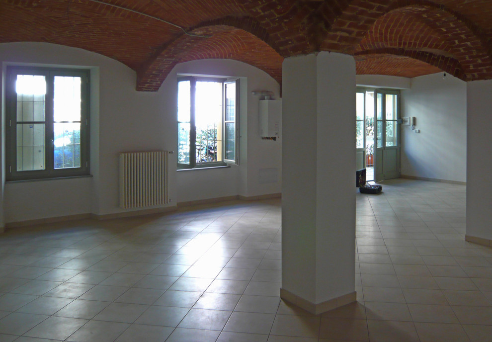 Design ideas for a large country look-out basement in Turin with white walls, ceramic floors, beige floor and vaulted.