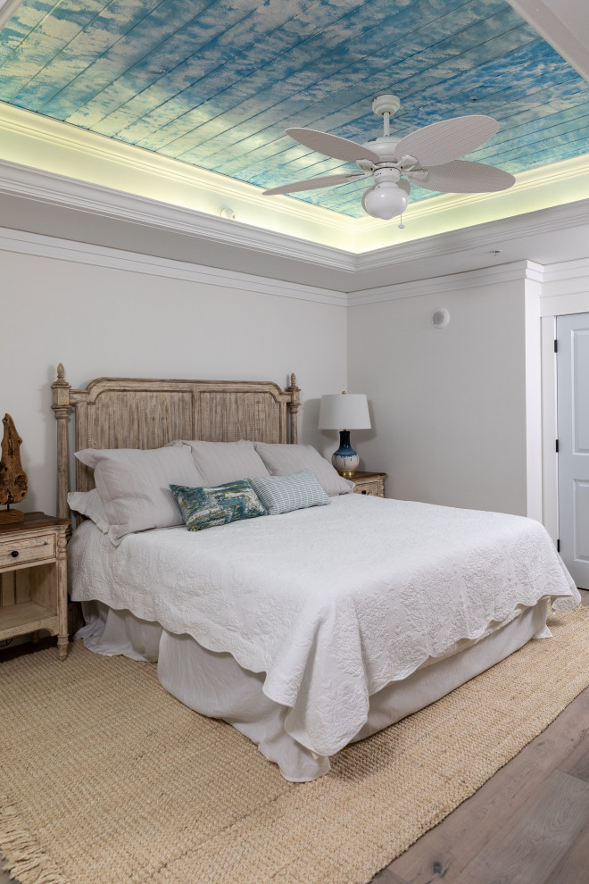 Ejemplo de dormitorio principal marinero de tamaño medio sin chimenea con paredes blancas, suelo de madera en tonos medios, suelo gris, bandeja y panelado