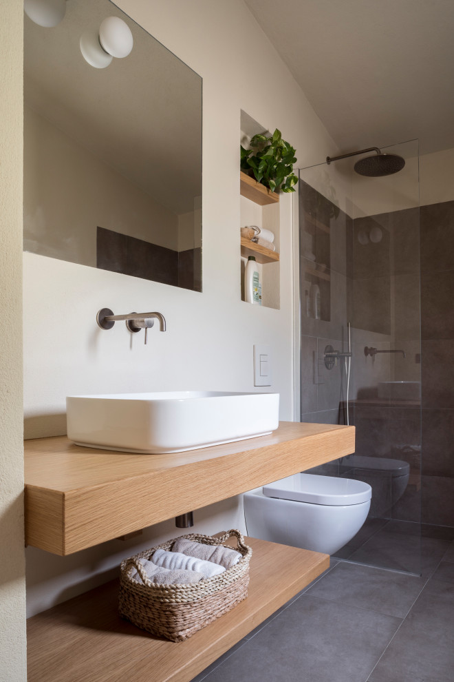 Example of a trendy master ceramic tile, gray floor and single-sink bathroom design in Cagliari with open cabinets, light wood cabinets, a two-piece toilet, beige walls, a trough sink, wood countertops, a niche and a floating vanity