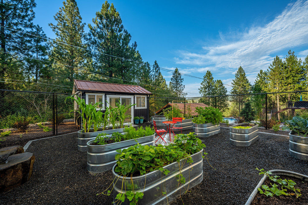 Expansive traditional side formal full sun garden in Seattle with a raised bed, gravel and a metal fence.
