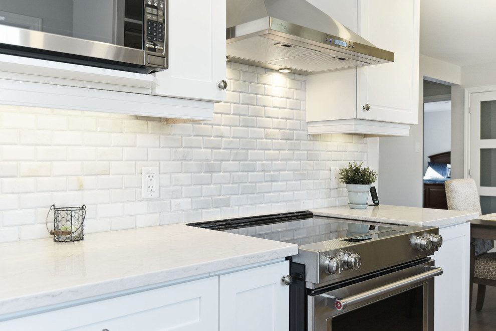Design ideas for a small contemporary galley eat-in kitchen in Toronto with a farmhouse sink, shaker cabinets, white cabinets, quartzite benchtops, white splashback, stone tile splashback, stainless steel appliances, light hardwood floors, no island, grey floor and white benchtop.