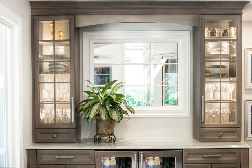 Inspiration for a large transitional single-wall medium tone wood floor and brown floor kitchen remodel in Denver with an undermount sink, recessed-panel cabinets, white backsplash, stone slab backsplash, stainless steel appliances, an island and brown cabinets