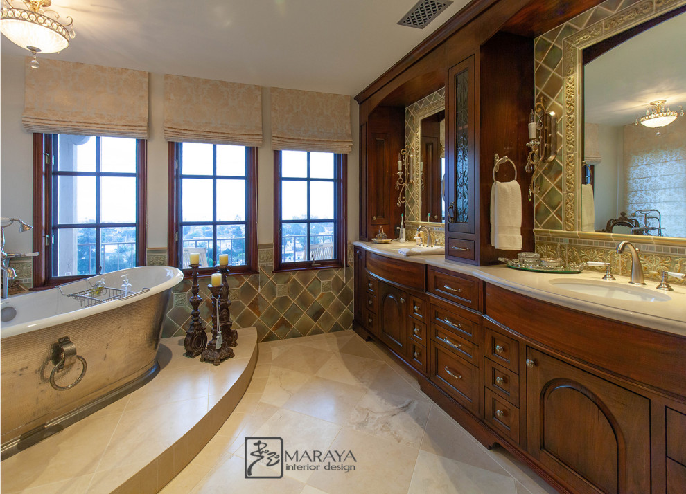 Photo of a mid-sized master bathroom in Santa Barbara with open cabinets, distressed cabinets, a freestanding tub, a corner shower, green tile, glass sheet wall, white walls, limestone floors, an undermount sink, limestone benchtops, black floor, a hinged shower door and beige benchtops.