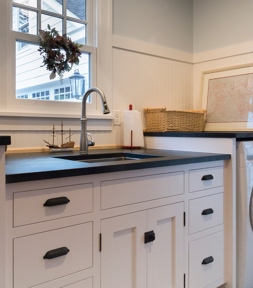 Mid-sized traditional galley dedicated laundry room in Chicago with an undermount sink, flat-panel cabinets, white cabinets, soapstone benchtops, porcelain floors, a side-by-side washer and dryer and grey walls.