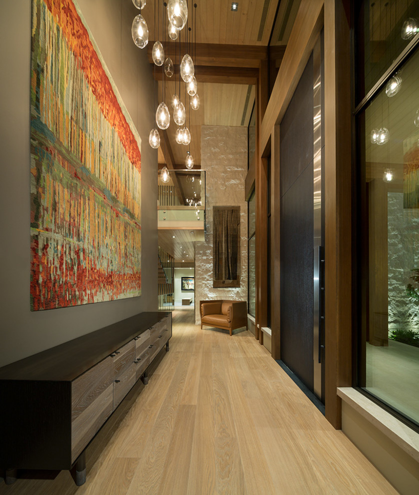 This is an example of an expansive modern hallway in Vancouver with grey walls and light hardwood floors.