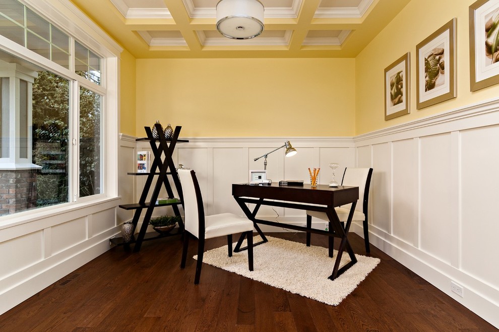 This is an example of a contemporary home office in Vancouver with yellow walls, dark hardwood floors and a freestanding desk.