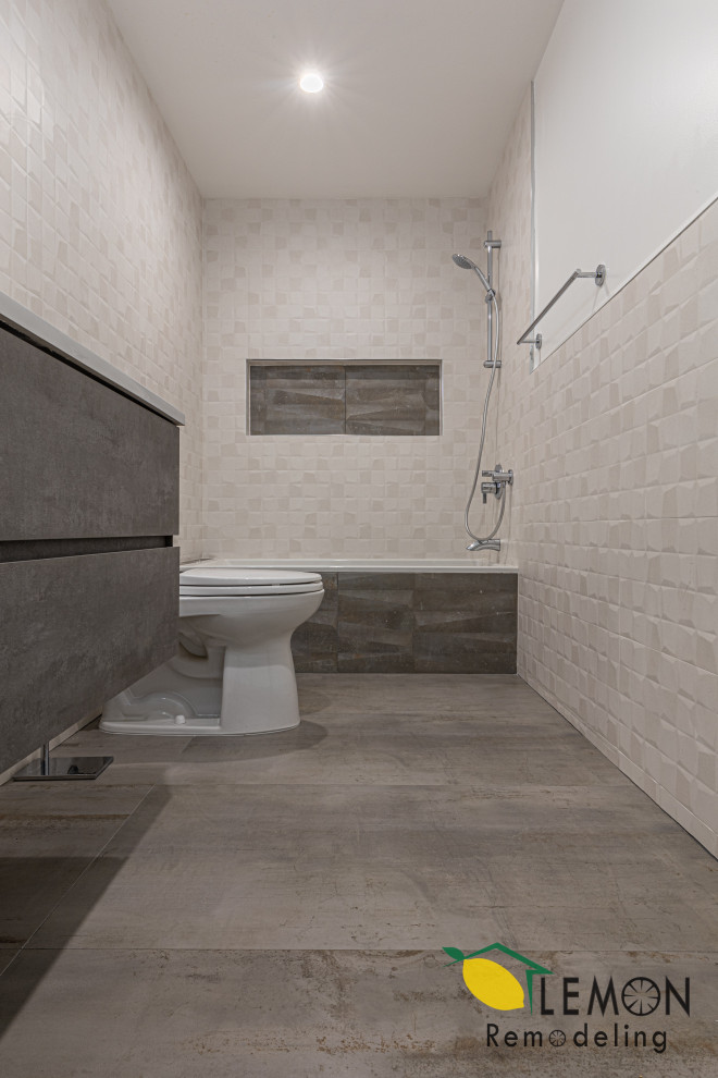 Cette image montre une salle de bain principale minimaliste avec meuble-lavabo suspendu, des portes de placard grises, un combiné douche/baignoire, un carrelage blanc, un mur blanc, un lavabo encastré, un sol gris, un plan de toilette blanc, une niche et meuble simple vasque.