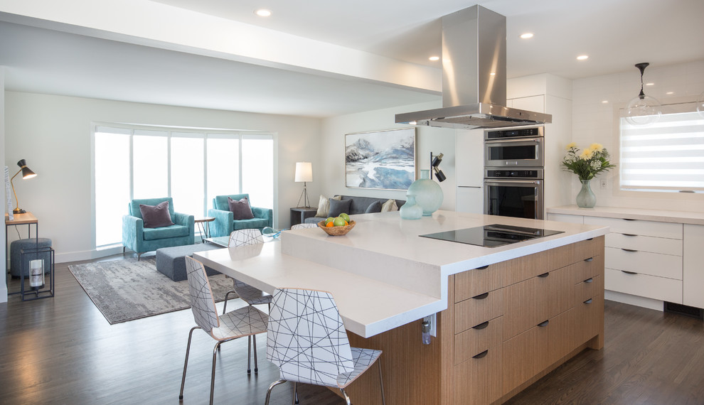 Mid-sized midcentury l-shaped eat-in kitchen in Calgary with an undermount sink, flat-panel cabinets, white cabinets, quartzite benchtops, white splashback, cement tile splashback, stainless steel appliances, medium hardwood floors, with island and brown floor.