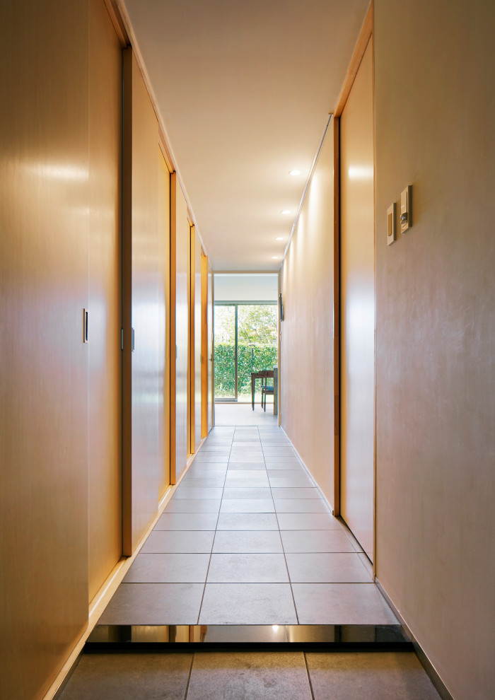 Ejemplo de recibidores y pasillos de tamaño medio con paredes blancas, suelo de baldosas de porcelana, suelo gris, machihembrado y machihembrado