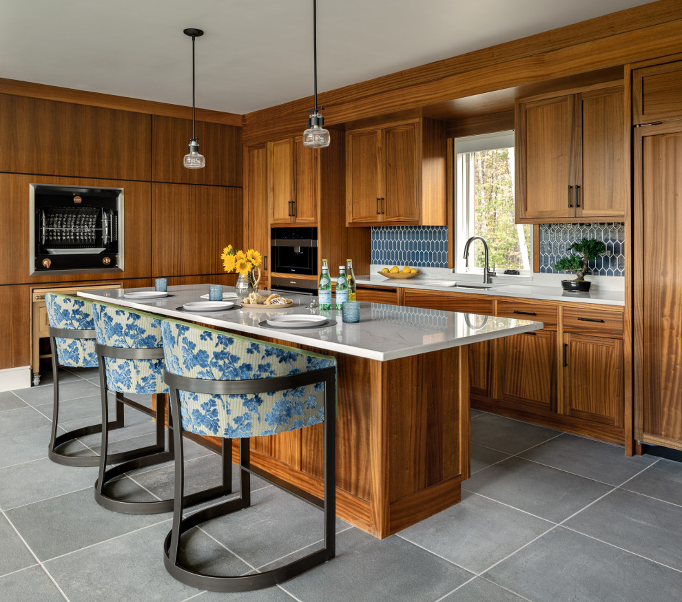 Transitional l-shaped gray floor kitchen photo with an undermount sink, shaker cabinets, medium tone wood cabinets, blue backsplash, mosaic tile backsplash, paneled appliances, an island and white countertops