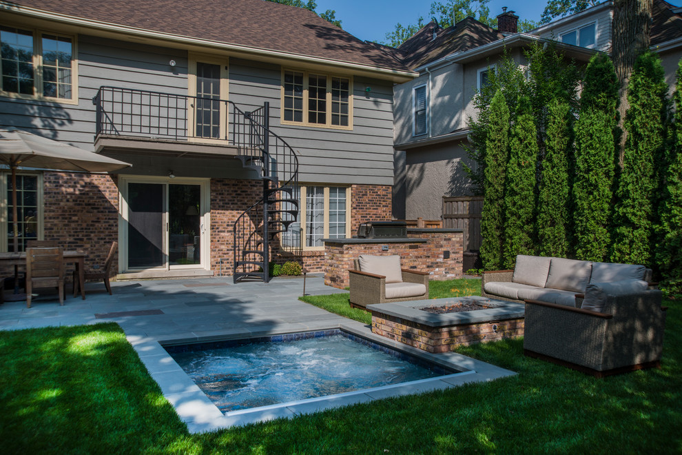 Photo of a small traditional backyard rectangular pool in Chicago with a hot tub and natural stone pavers.