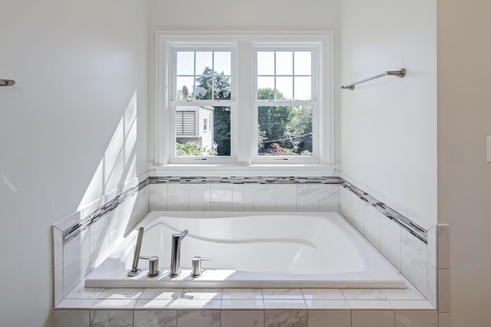 This is an example of a master bathroom in DC Metro with an undermount sink, dark wood cabinets, marble benchtops, a drop-in tub, a corner shower, a two-piece toilet, white tile, white walls and ceramic floors.