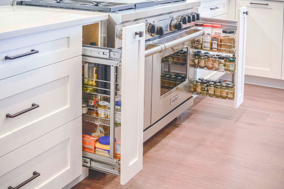 Example of a mid-sized transitional u-shaped medium tone wood floor and brown floor home design design in Calgary with an undermount sink, flat-panel cabinets, white cabinets, marble countertops, gray backsplash, ceramic backsplash, paneled appliances and an island