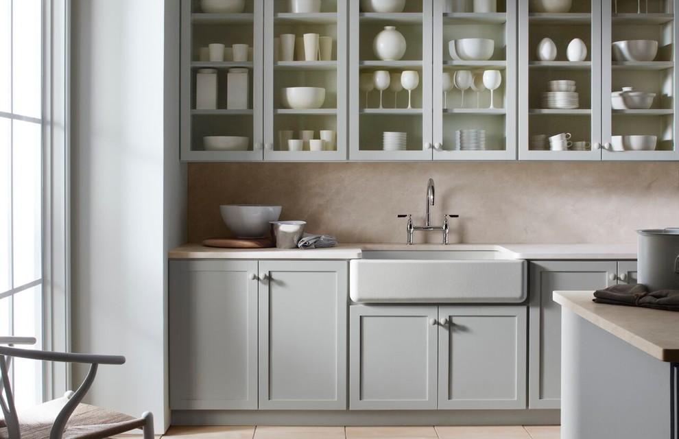 Eat-in kitchen - mid-sized transitional eat-in kitchen idea in Providence with a farmhouse sink, glass-front cabinets, distressed cabinets, solid surface countertops, beige backsplash and an island