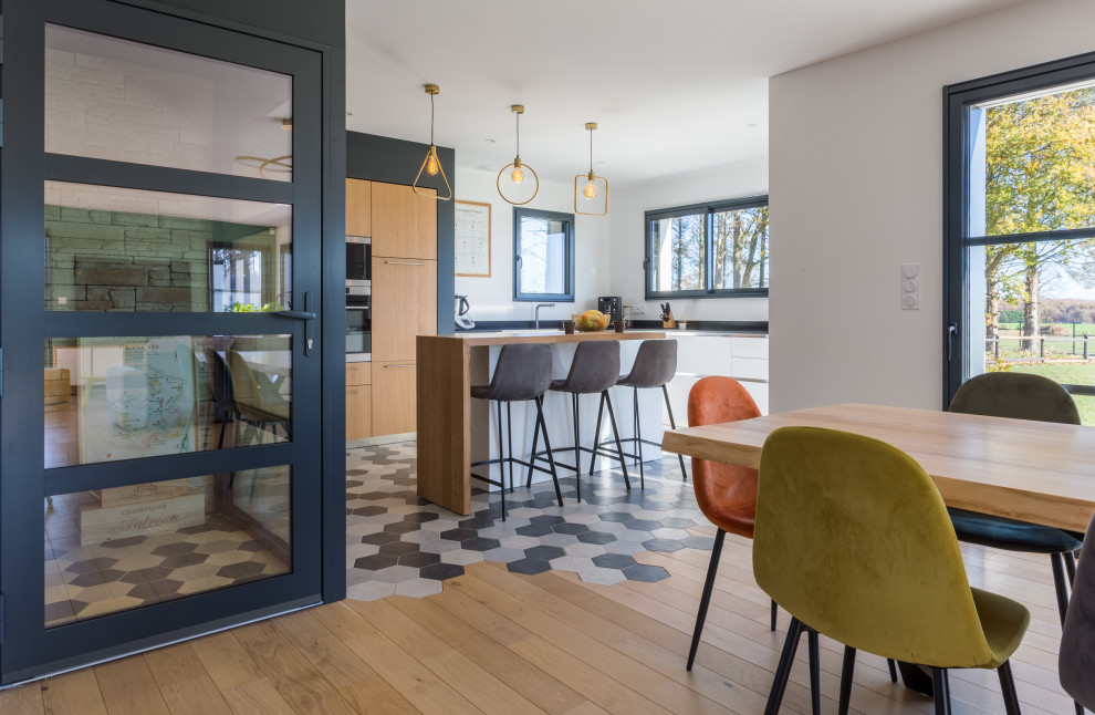 Inspiration for a large modern l-shaped open plan kitchen in Rennes with an integrated sink, beaded cabinets, white cabinets, granite worktops, black splashback, granite splashback, stainless steel appliances, cement flooring, an island, grey floors and black worktops.