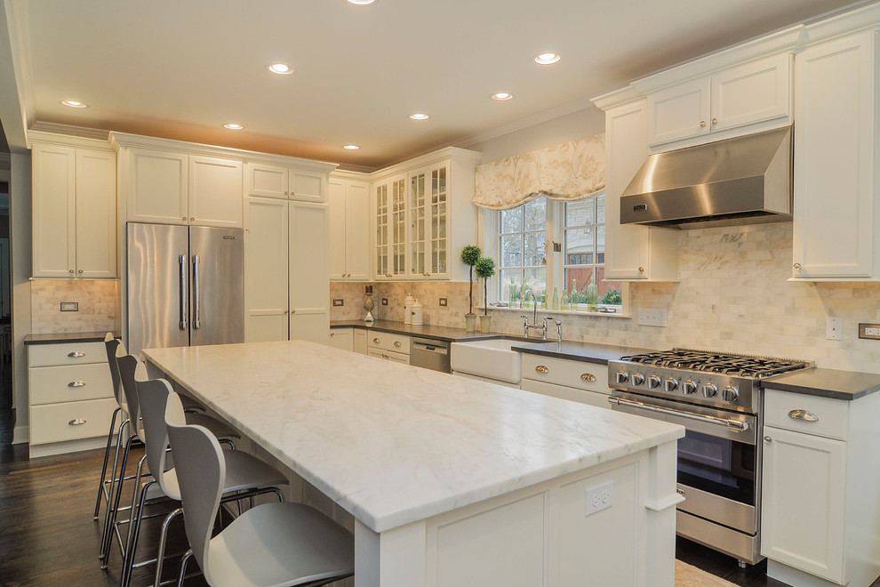 Traditional l-shaped eat-in kitchen in Nashville with a farmhouse sink, shaker cabinets, white cabinets, marble benchtops, white splashback, stone tile splashback and stainless steel appliances.