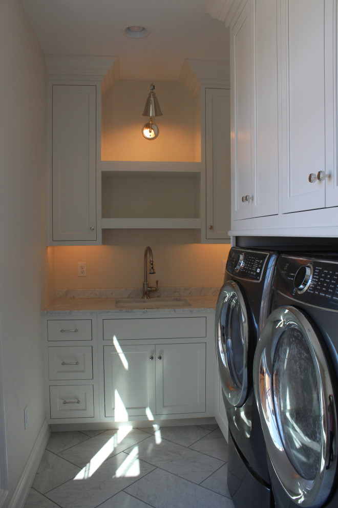 Photo of a contemporary laundry room in Other with an undermount sink, white cabinets, white walls, a side-by-side washer and dryer, grey floor and grey benchtop.