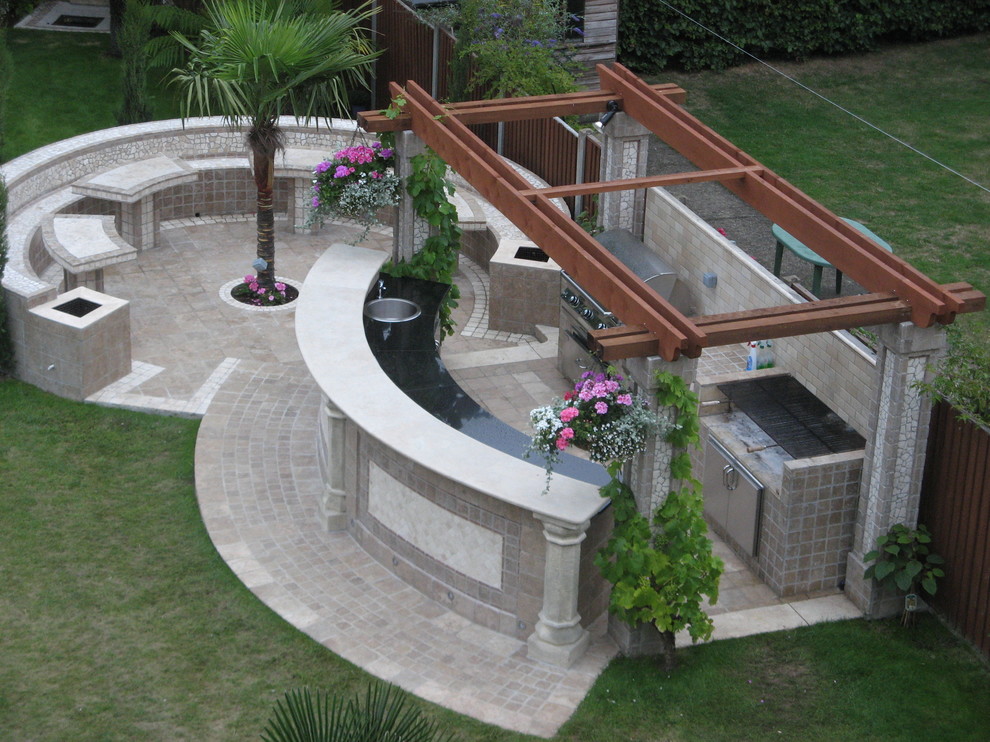 Photo of a large modern backyard patio in Buckinghamshire with an outdoor kitchen and tile.