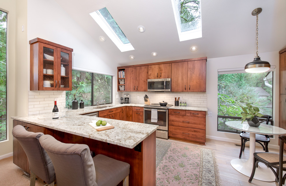Photo of a transitional u-shaped eat-in kitchen in Seattle with an undermount sink, flat-panel cabinets, medium wood cabinets, brick splashback, stainless steel appliances, light hardwood floors and a peninsula.