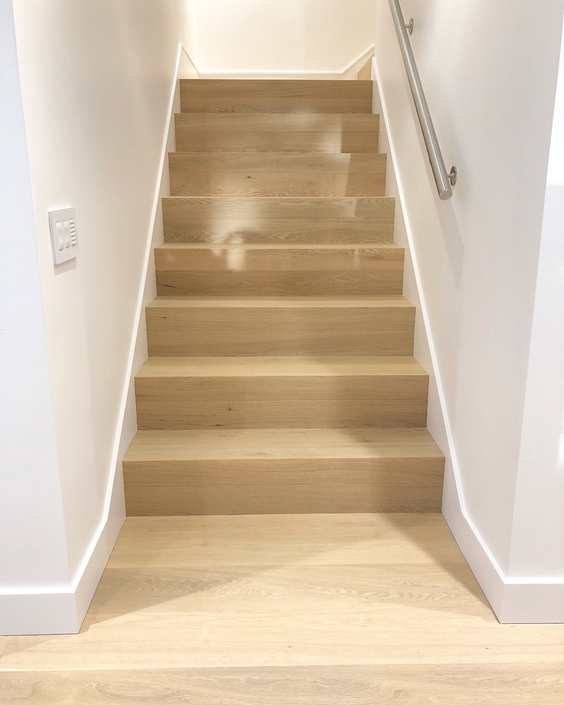 Photo of a mid-sized modern wood straight staircase in Vancouver with wood risers and metal railing.