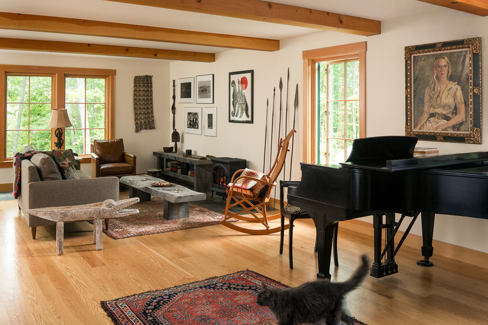 This is an example of a country open concept family room in Portland Maine with a music area, beige walls and light hardwood floors.