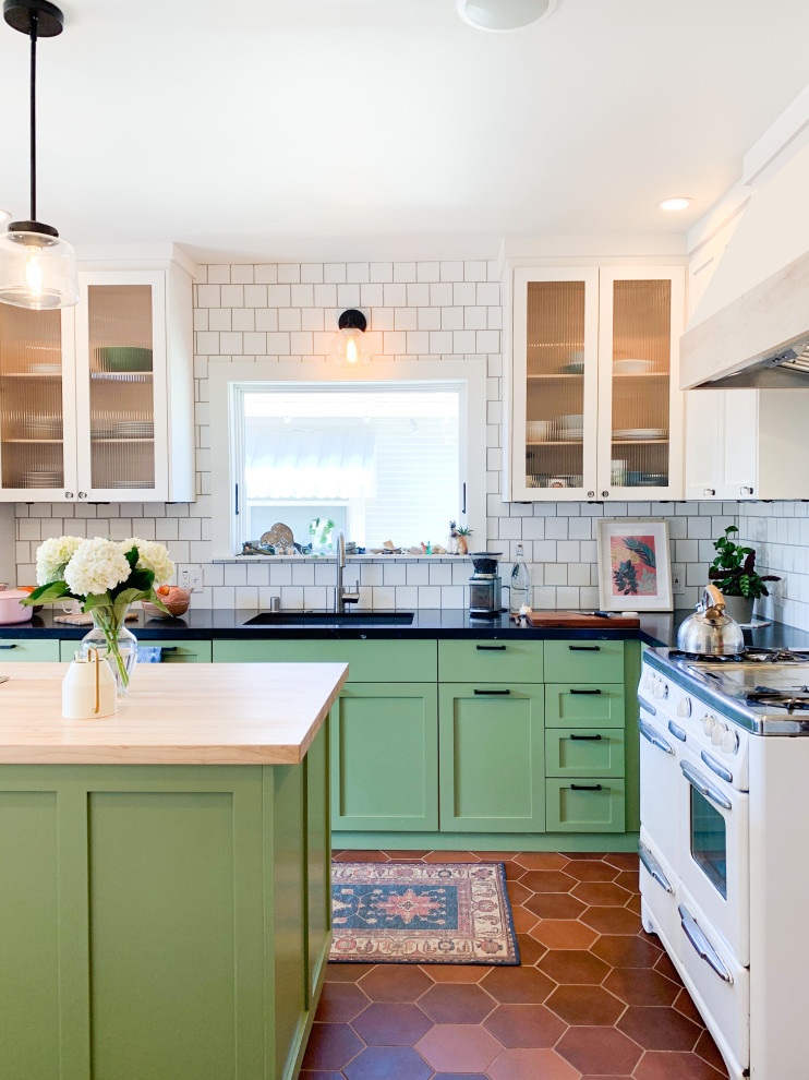 Design ideas for a large transitional l-shaped kitchen in San Francisco with an undermount sink, green cabinets, white splashback, ceramic splashback, ceramic floors, with island, brown floor, black benchtop, shaker cabinets and white appliances.