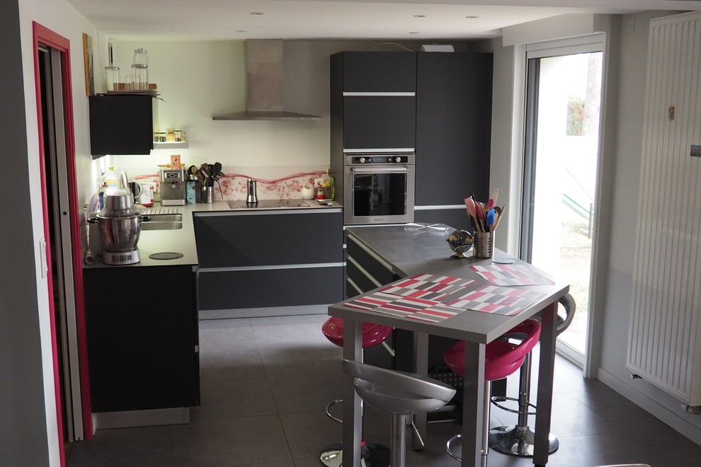 Photo of a small contemporary l-shaped open plan kitchen in Nantes with a double-bowl sink, flat-panel cabinets, grey cabinets, stainless steel benchtops, pink splashback, glass sheet splashback, stainless steel appliances, ceramic floors, with island and grey floor.