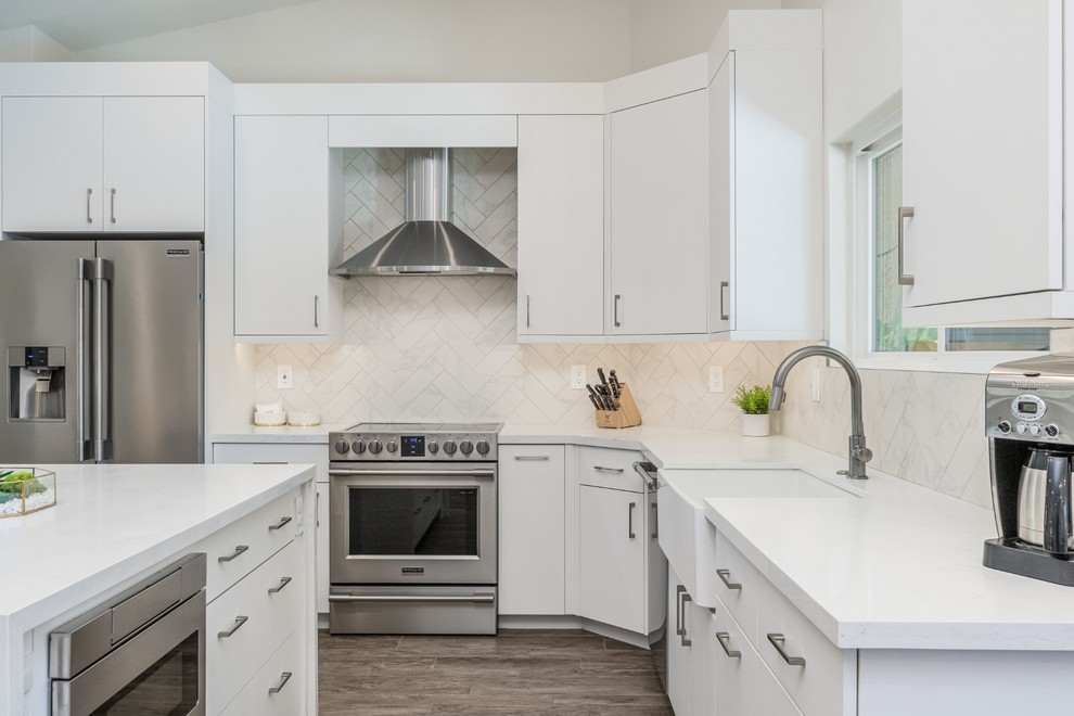 Design ideas for a mid-sized midcentury l-shaped eat-in kitchen in Phoenix with a farmhouse sink, flat-panel cabinets, white cabinets, quartzite benchtops, white splashback, porcelain splashback, stainless steel appliances, porcelain floors, with island, beige floor and white benchtop.