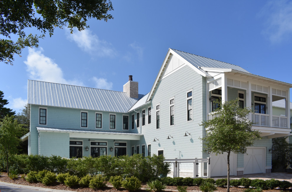 Idée de décoration pour une façade de maison bleue marine en bois et bardeaux à un étage avec un toit à deux pans, un toit en métal et un toit gris.