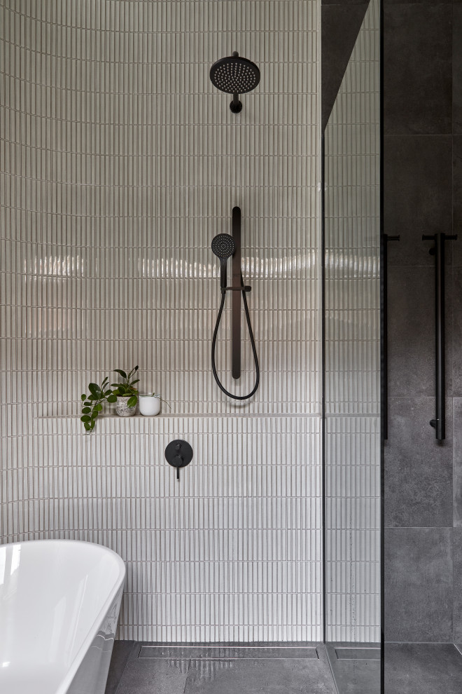 This is an example of a mid-sized contemporary master bathroom in Melbourne with flat-panel cabinets, grey cabinets, a freestanding tub, an open shower, a wall-mount toilet, multi-coloured tile, porcelain tile, multi-coloured walls, porcelain floors, a vessel sink, tile benchtops, grey floor, an open shower, grey benchtops, a single vanity, a built-in vanity and vaulted.
