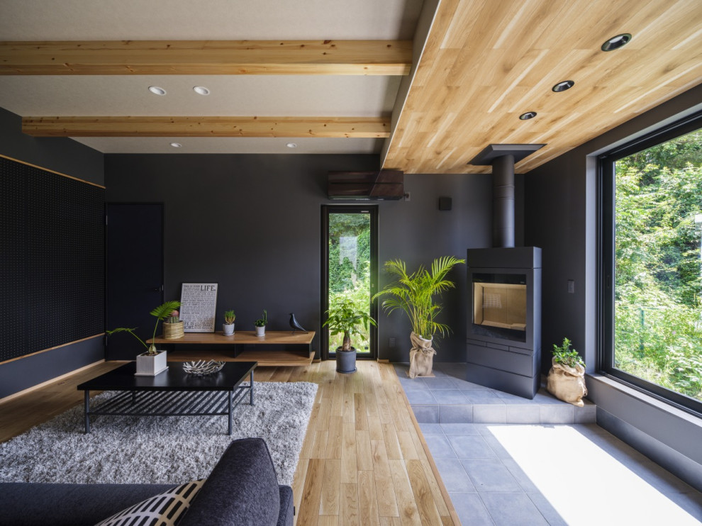 This is an example of a medium sized modern grey and brown open plan living room in Other with black walls, light hardwood flooring, a wood burning stove, a tiled fireplace surround, a freestanding tv, brown floors, a wallpapered ceiling and wallpapered walls.