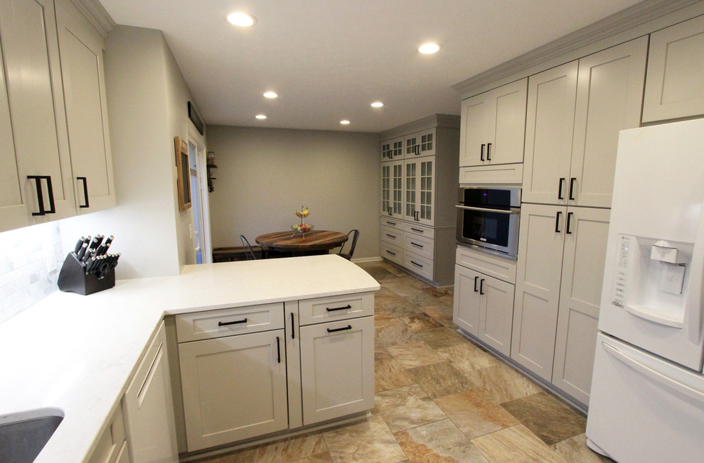 Mid-sized transitional u-shaped eat-in kitchen in Cleveland with an undermount sink, flat-panel cabinets, grey cabinets, quartz benchtops, grey splashback, marble splashback, white appliances, a peninsula, white benchtop and multi-coloured floor.