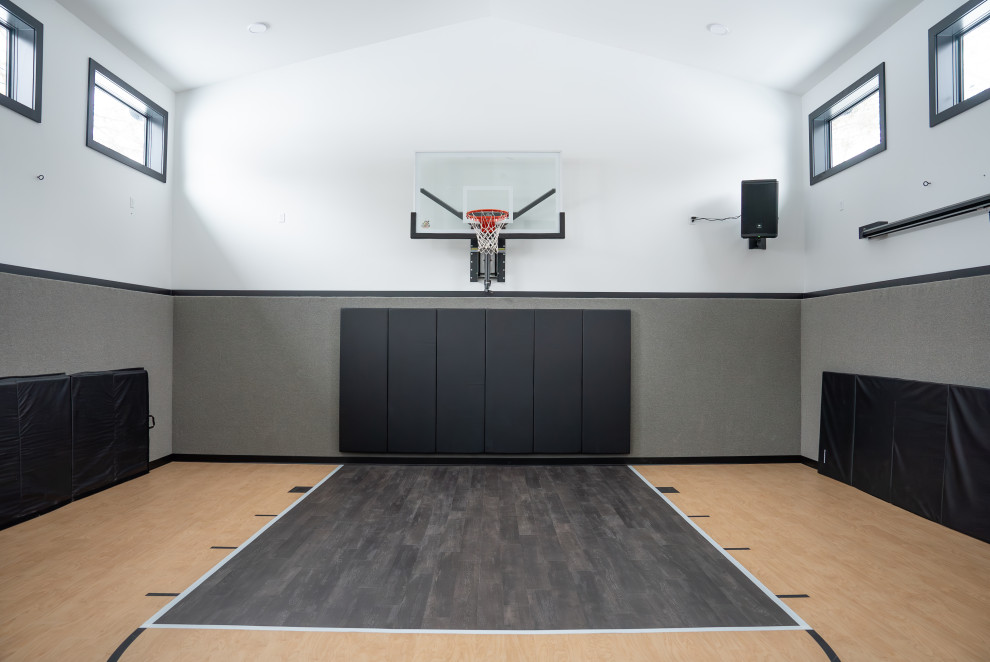 This is an example of a mid-sized contemporary indoor sport court in Minneapolis with white walls, laminate floors, brown floor and vaulted.