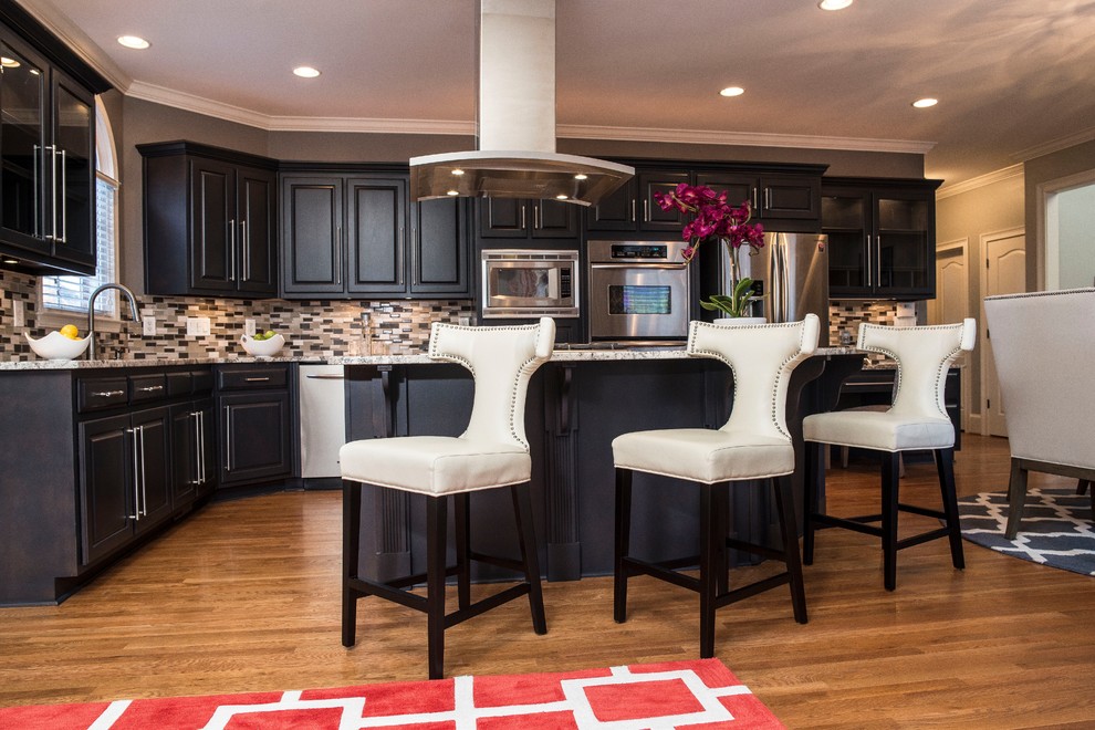 Mid-sized transitional l-shaped medium tone wood floor and brown floor kitchen photo in Atlanta with an undermount sink, shaker cabinets, black cabinets, marble countertops, glass tile backsplash, stainless steel appliances and an island