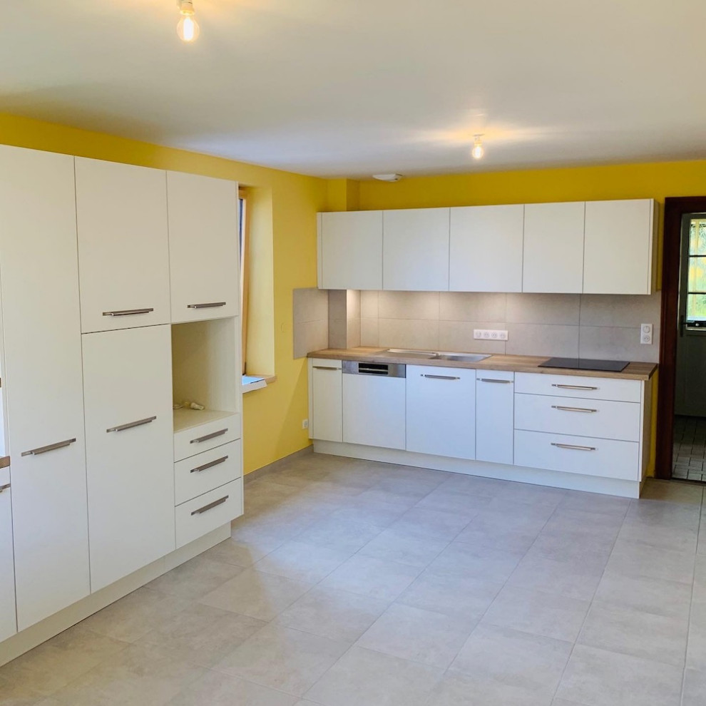 Inspiration pour cuisine ouverte in L With un évier intégré, un placard à porte affleurante, des portes de placard blanches, un plan de travail en bois, une crédence grise, une crédence en céramique, aucun îlot and un plan de travail blanc.