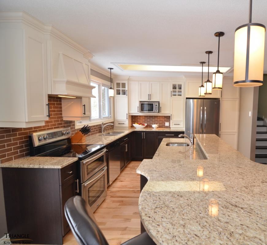 Inspiration for a large transitional l-shaped light wood floor kitchen remodel in Ottawa with an undermount sink, recessed-panel cabinets, white cabinets, granite countertops, red backsplash, brick backsplash, stainless steel appliances and an island