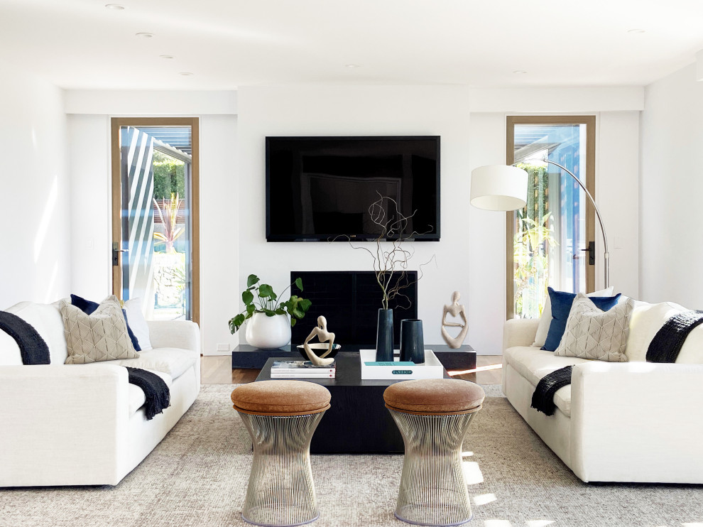 Example of a large trendy enclosed medium tone wood floor and beige floor living room design in San Diego with white walls, a standard fireplace and a plaster fireplace