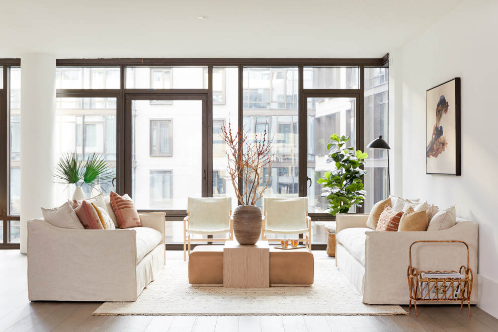 This is an example of a contemporary formal open concept living room in New York with white walls, medium hardwood floors, no fireplace, no tv and brown floor.