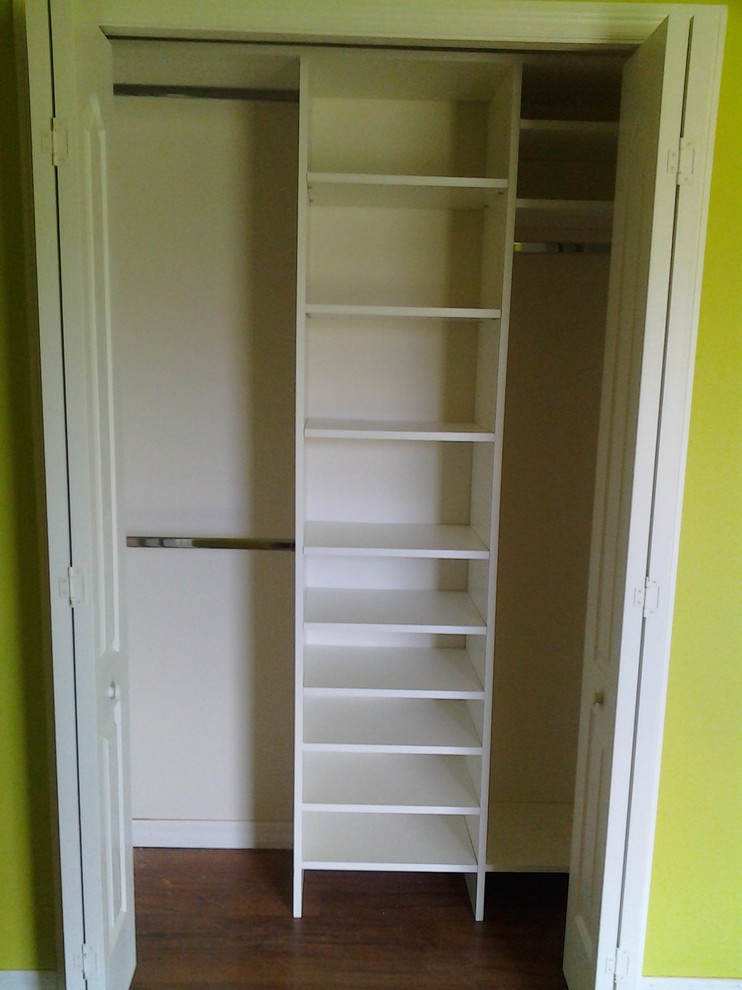 This is an example of a contemporary built-in wardrobe in Orlando with white cabinets and dark hardwood floors.