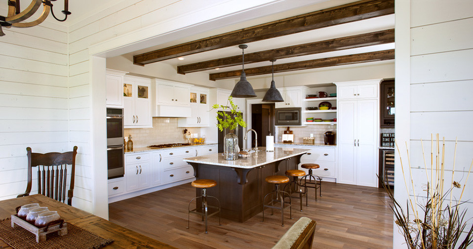 Example of a l-shaped kitchen design with stainless steel appliances and an island
