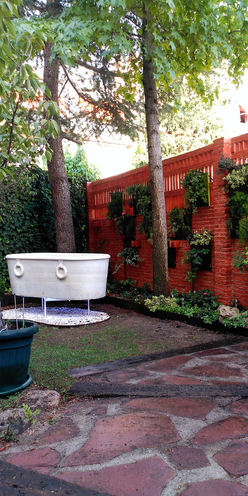 This is an example of a mid-sized contemporary courtyard partial sun driveway in Madrid with a vertical garden and natural stone pavers.