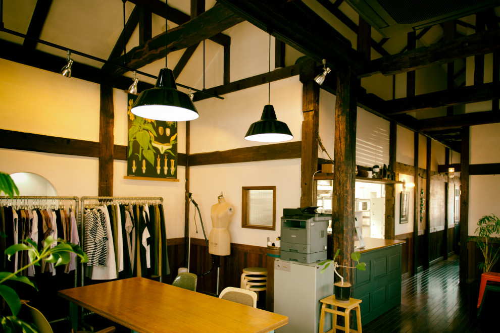 Geräumiges Industrial Arbeitszimmer ohne Kamin mit Studio, weißer Wandfarbe, dunklem Holzboden, freistehendem Schreibtisch, braunem Boden und freigelegten Dachbalken in Tokio Peripherie