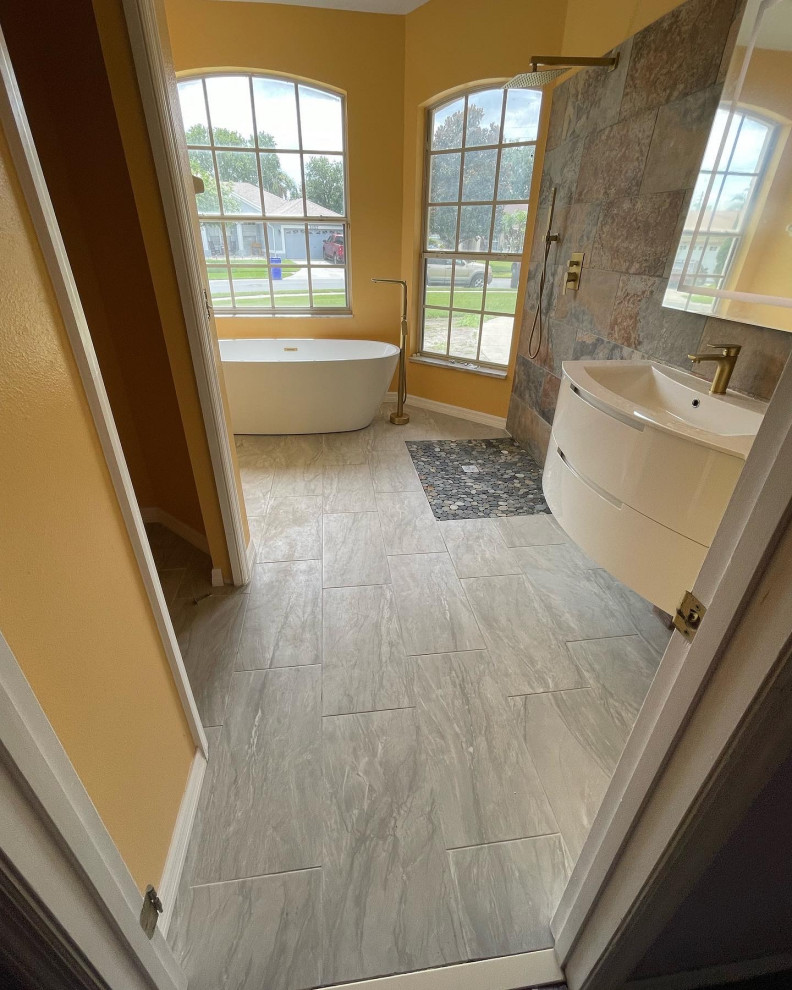 Пример оригинального дизайна: ванная комната среднего размера в стиле модернизм с белыми фасадами, отдельно стоящей ванной, душем без бортиков, раздельным унитазом, серой плиткой, керамогранитной плиткой, желтыми стенами, полом из керамогранита, монолитной раковиной, мраморной столешницей, серым полом, открытым душем, белой столешницей, тумбой под одну раковину и подвесной тумбой
