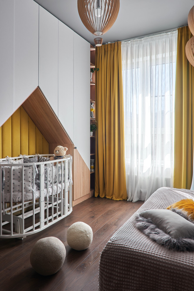 Modelo de habitación de bebé niña urbana de tamaño medio con paredes grises, suelo de madera en tonos medios, suelo marrón y ladrillo