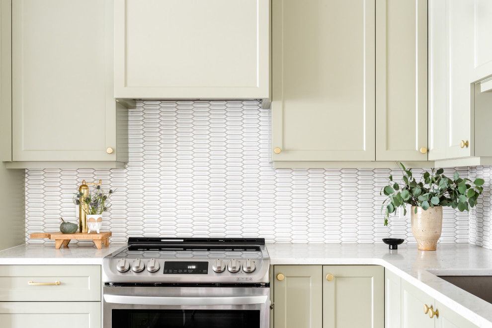 Small transitional brown floor kitchen photo with shaker cabinets, green cabinets, white backsplash, stainless steel appliances, an island and white countertops