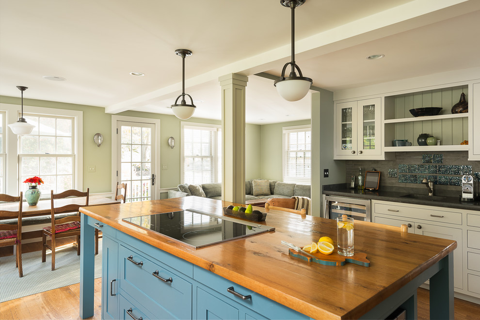This is an example of a large traditional u-shaped kitchen in Boston with an undermount sink, shaker cabinets, white cabinets, wood benchtops, stainless steel appliances, with island, grey splashback and medium hardwood floors.